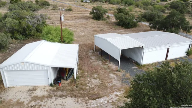 a view of a barn with large trees and a yard