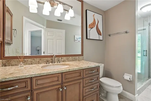 a bathroom with a granite countertop toilet a sink and a mirror