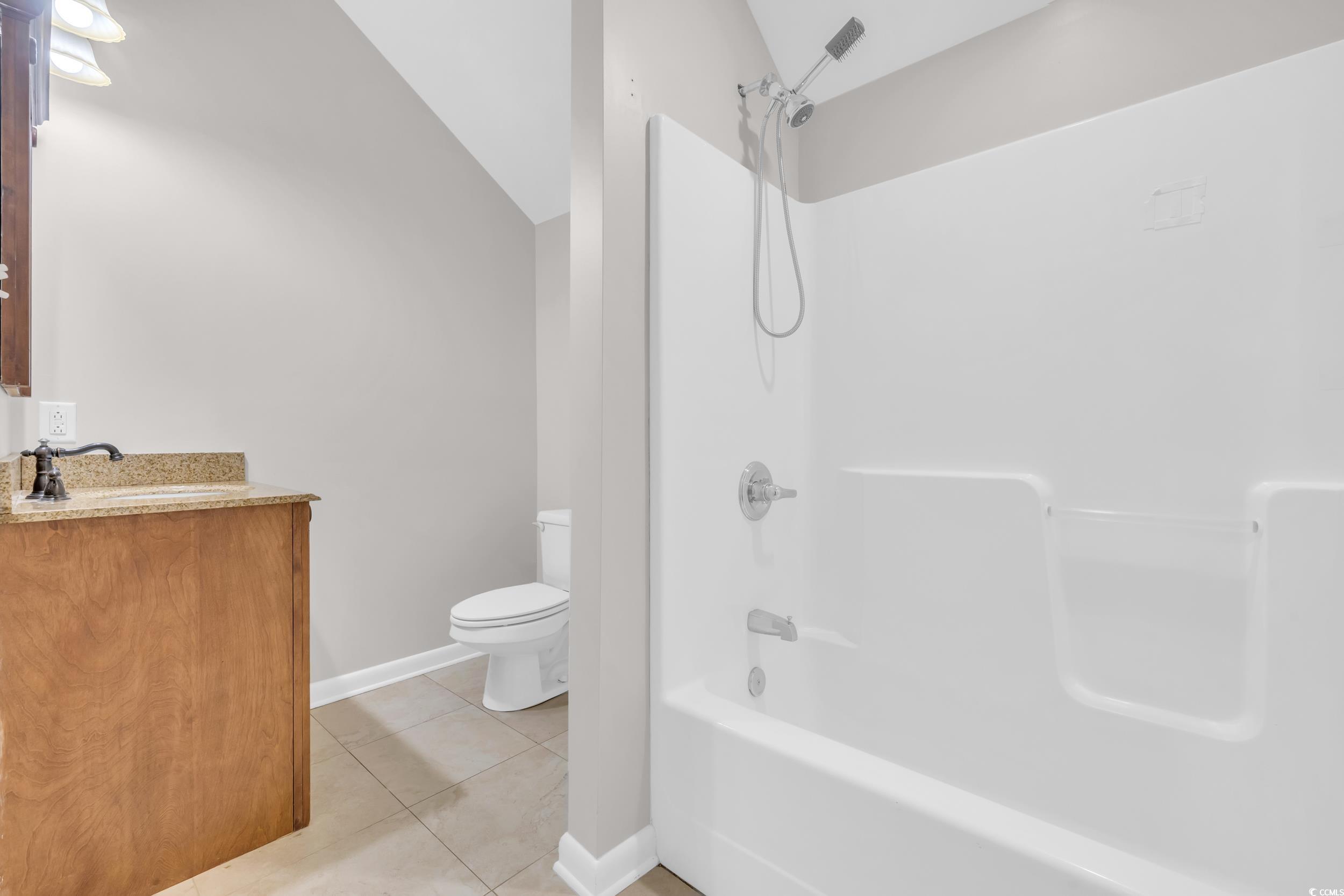 208 Lander Drive Conway, SC 29526 - Photo 30 of 40 Bathroom featuring shower / washtub combination, light tile patterned floors, vanity, and vaulted ceiling