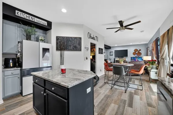 a open kitchen with stainless steel appliances granite countertop a table chairs and a refrigerator