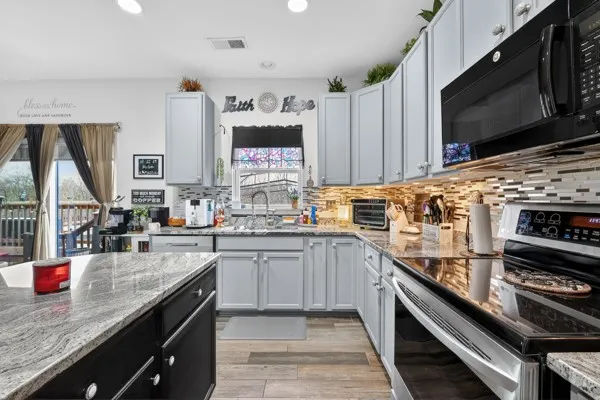 a kitchen with stainless steel appliances kitchen island granite countertop a sink stove and microwave