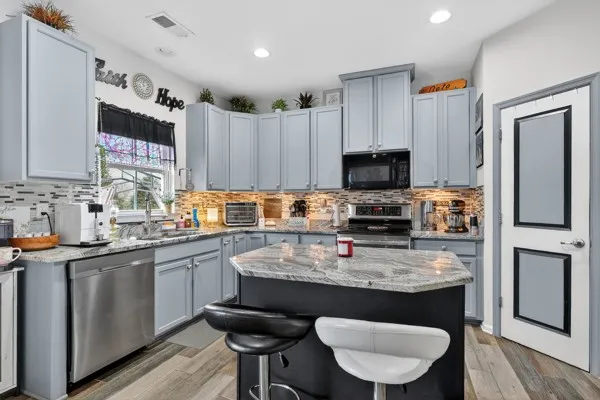 a kitchen with granite countertop a sink cabinets and stainless steel appliances