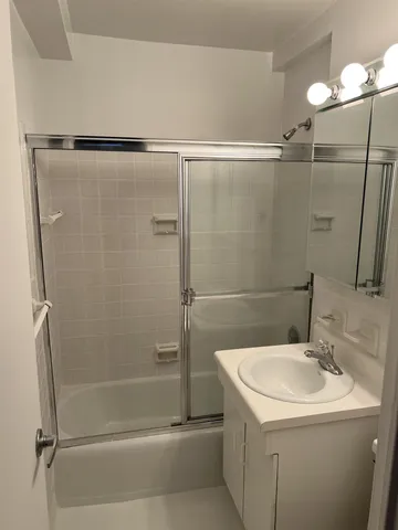 a bathroom with a shower sink vanity and toilet