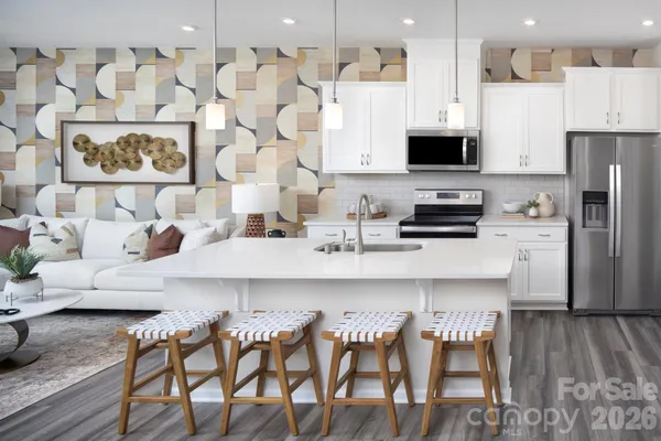 a kitchen with stainless steel appliances kitchen island granite countertop a refrigerator a stove a sink and white cabinets with wooden floor