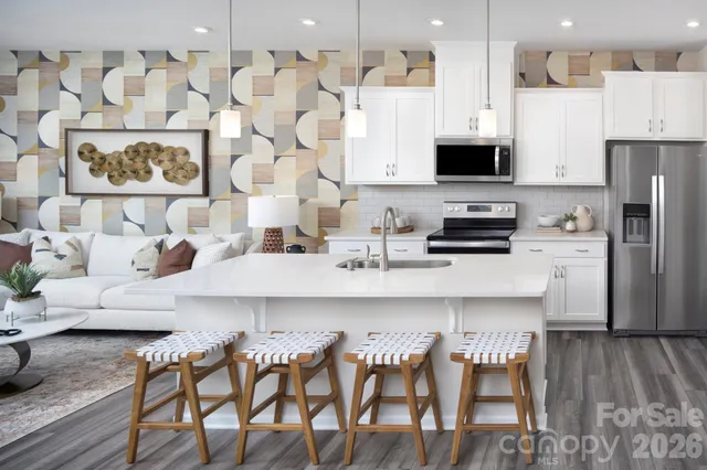 a kitchen with stainless steel appliances kitchen island granite countertop a refrigerator a stove a sink and white cabinets with wooden floor