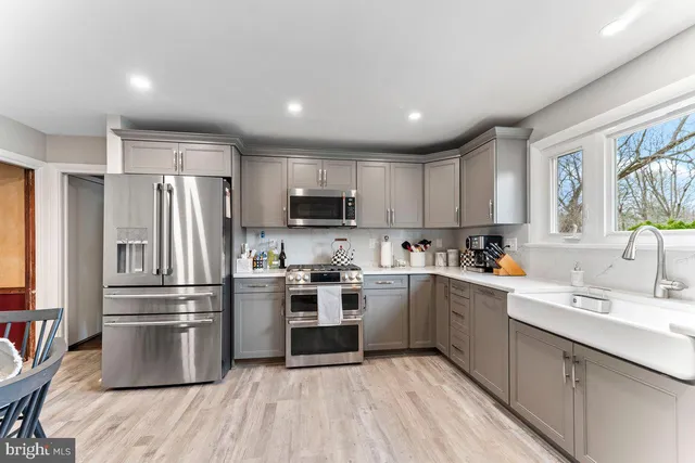 a kitchen with white cabinets a sink a window and stainless steel appliances
