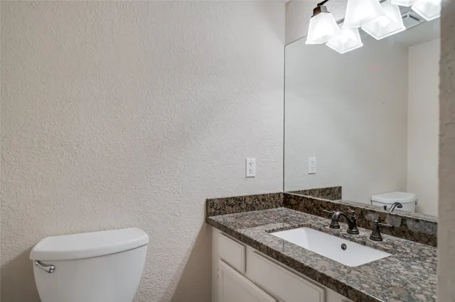a bathroom with a granite countertop sink a toilet and a mirror