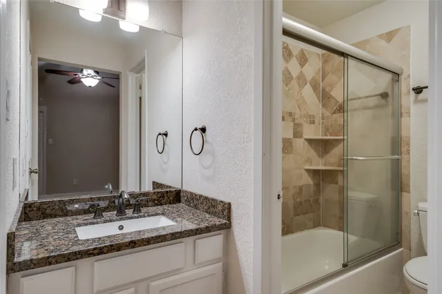 a bathroom with a granite countertop sink toilet and shower