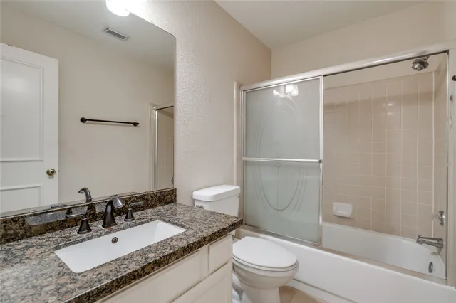 a bathroom with a granite countertop sink toilet and shower