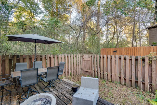 a view of a patio with a table and chairs under an umbrella with wooden fence