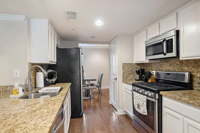 a kitchen with granite countertop kitchen island stainless steel appliances a stove sink and microwave