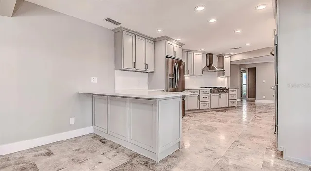 a kitchen with stainless steel appliances kitchen island granite countertop a refrigerator and a sink