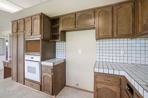 a large kitchen with kitchen island a large window a sink and stainless steel appliances