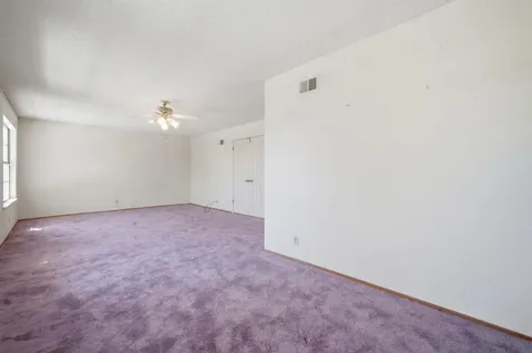 a view of an empty room with fireplace and a window