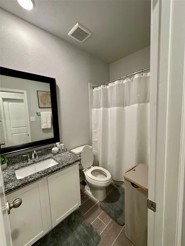 a bathroom with a granite countertop sink toilet and mirror