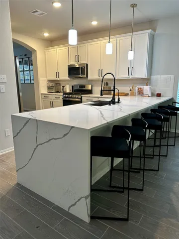 a kitchen with stainless steel appliances kitchen island granite countertop a sink a stove and cabinets