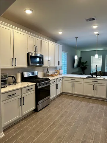 a large kitchen with cabinets a sink and a stove top oven with wooden floor