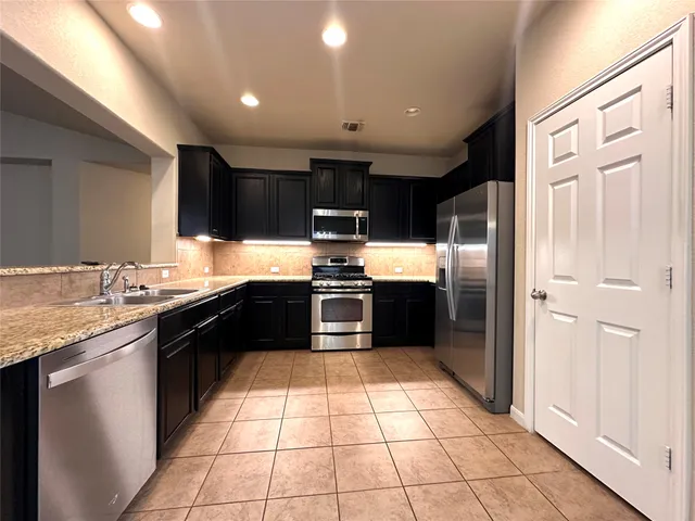 a kitchen with a refrigerator sink and wooden cabinets