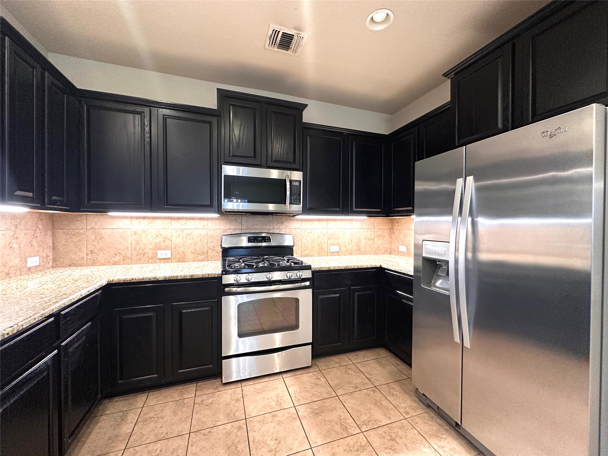 1000 Drake Cove Leander, TX 78641 - Photo 12 of 24 a kitchen with a refrigerator sink and wooden cabinets