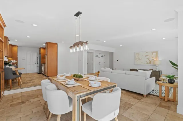 a view of a dining room and livingroom with furniture wooden floor a rug a chandelier and a mirror
