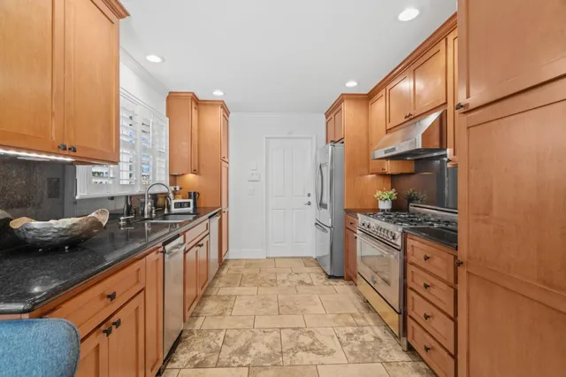 a kitchen with stainless steel appliances granite countertop a stove a sink and a refrigerator
