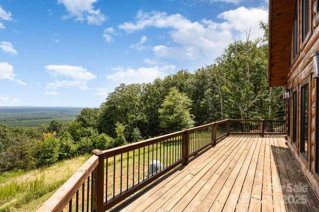 a view of balcony with wooden floor and trees in the background
