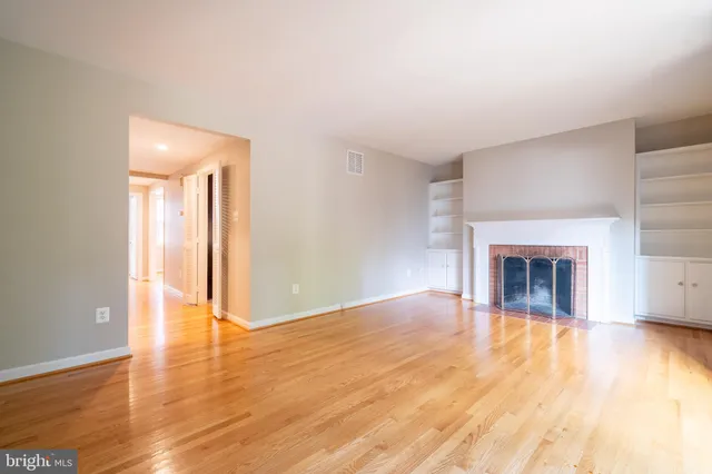 an empty room with wooden floor and fireplace