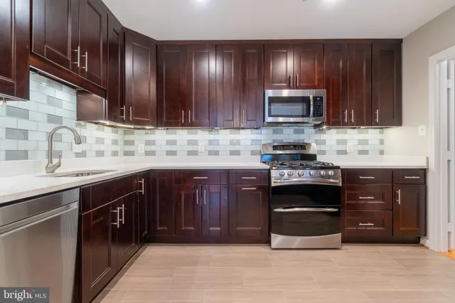 a kitchen with stainless steel appliances granite countertop wooden cabinets and a sink