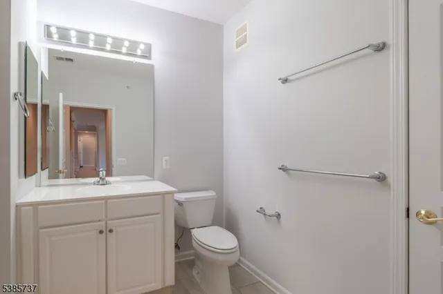 a bathroom with a toilet sink vanity and mirror