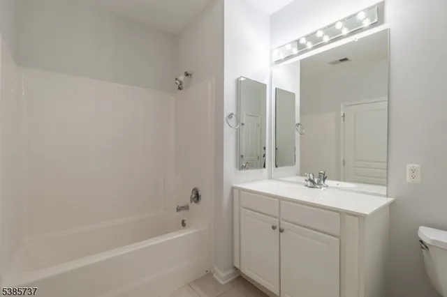 a bathroom with a tub sink double vanity and mirror