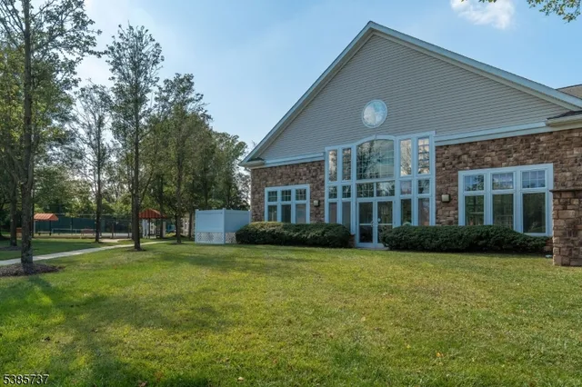 a view of a house next to a big yard and large trees