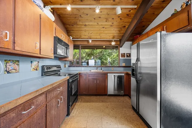 a kitchen with stainless steel appliances granite countertop a refrigerator a sink a stove and a wooden floors