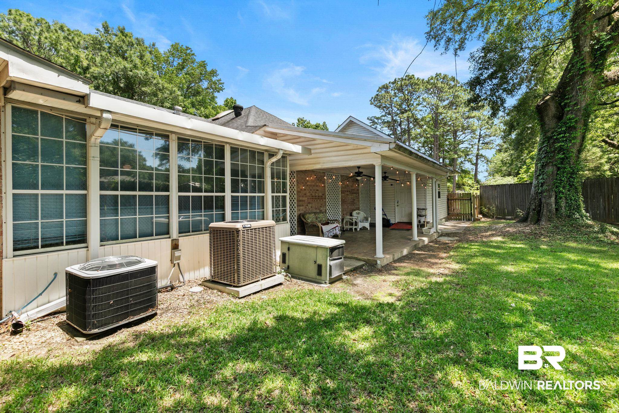 927 Cleveland Road Saraland, AL 36571 - Photo 61 of 80 Expansive backyard featuring a covered patio with ceiling fans, a separate sunroom, mature trees, and a wooden privacy fence