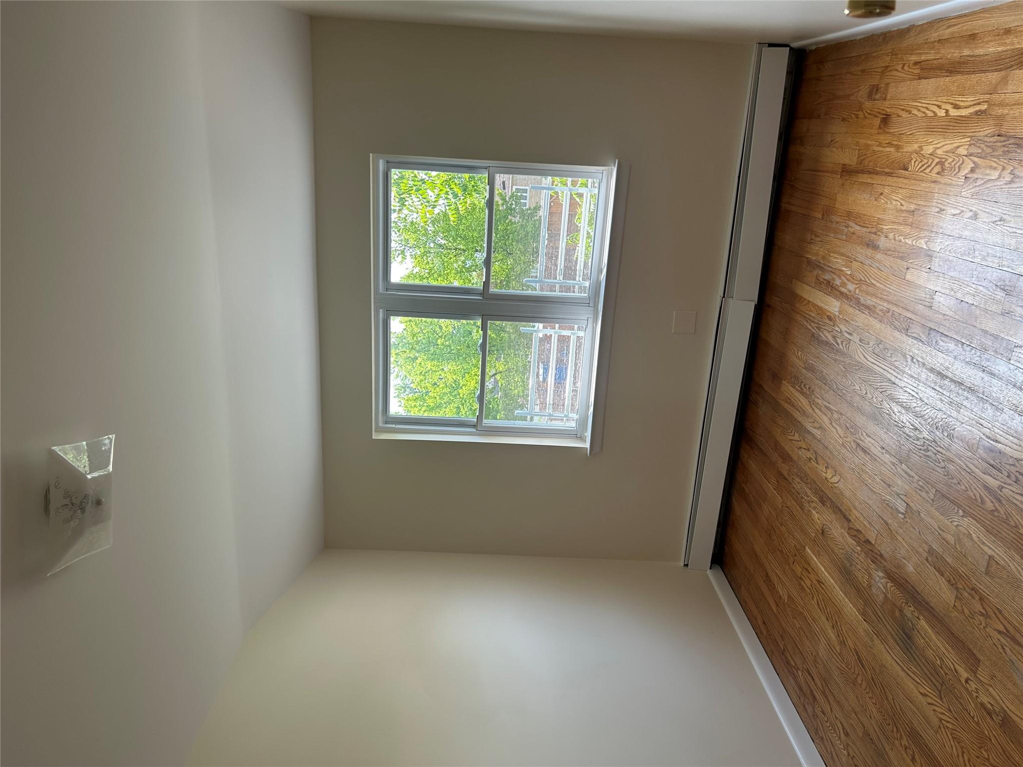 206-18 45th Road, Unit SECOND Queens, NY 11361 - Photo 11 of 14 Unfurnished room featuring a baseboard radiator, wood finished floors, and baseboards