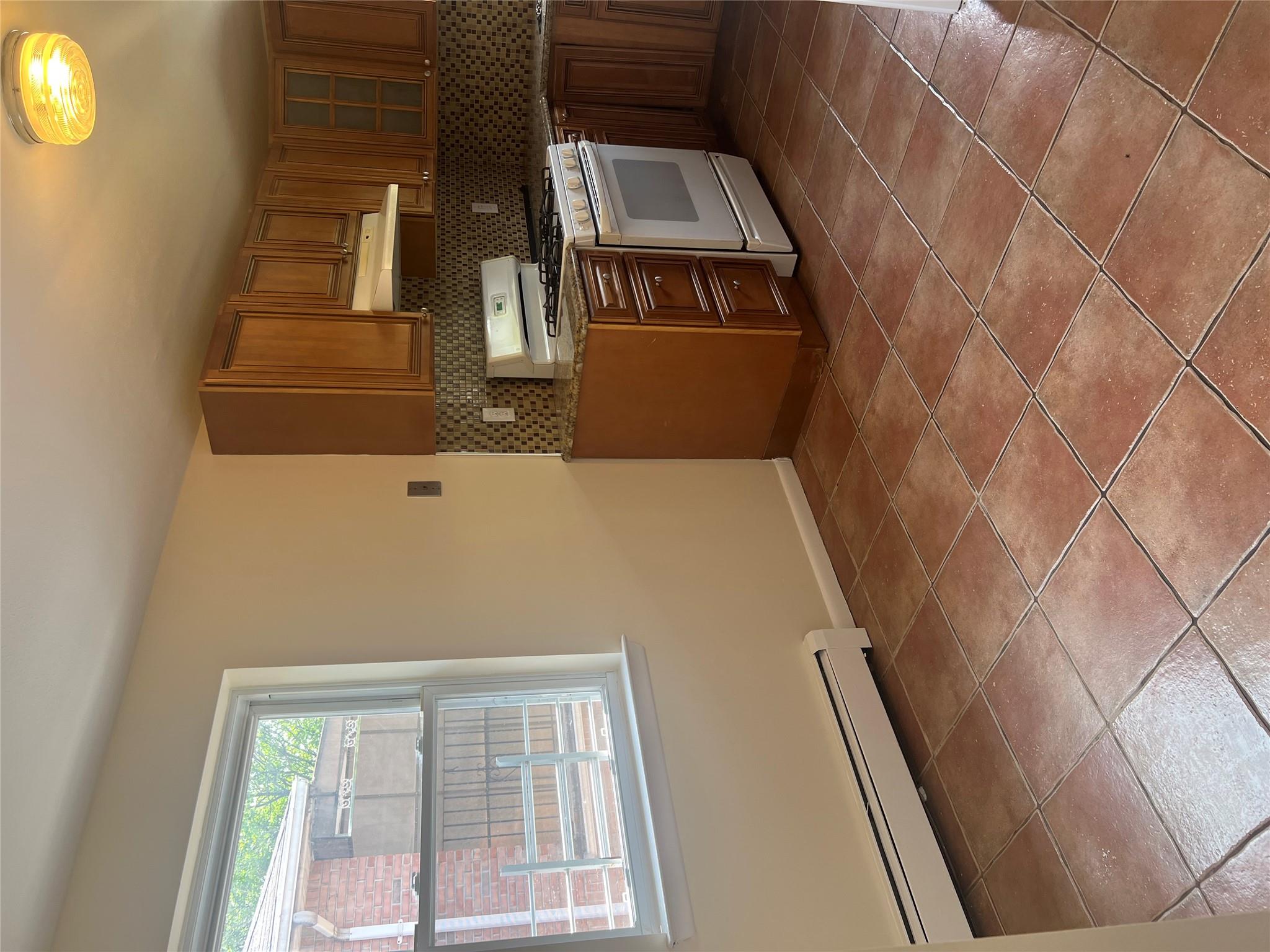 206-18 45th Road, Unit SECOND Queens, NY 11361 - Photo 4 of 14 Kitchen with range, baseboard heating, extractor fan, light tile patterned flooring, and backsplash