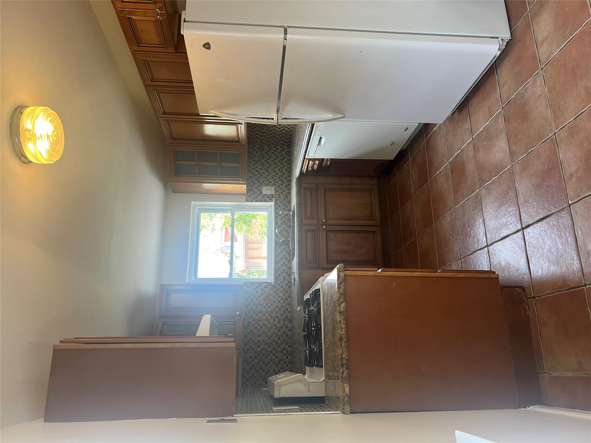 206-18 45th Road, Unit SECOND Queens, NY 11361 - Photo 5 of 14 Kitchen featuring refrigerator, dishwashing machine, range, brown cabinetry, and backsplash