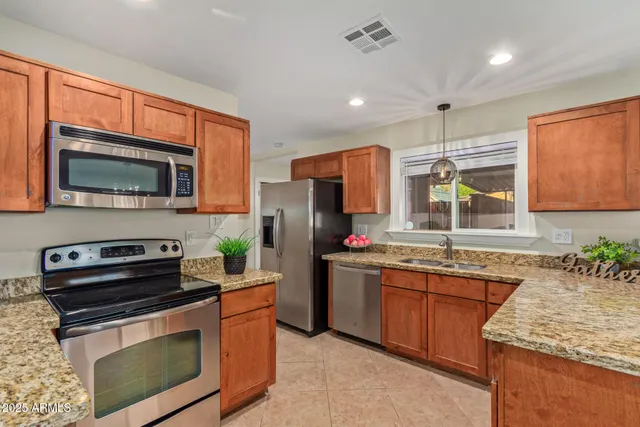 a kitchen with stainless steel appliances granite countertop a stove a sink and a microwave