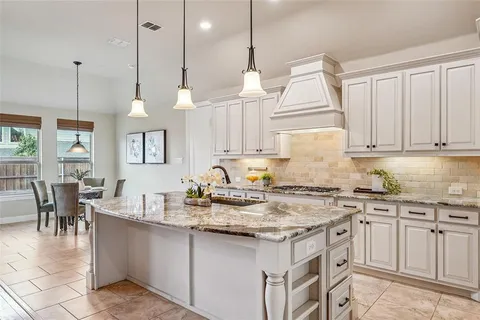 a kitchen with kitchen island granite countertop a sink a counter space appliances and cabinets