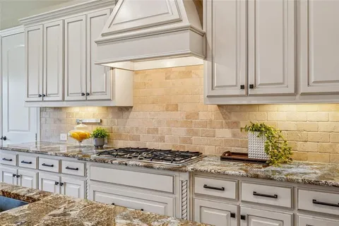 a kitchen with granite countertop a stove a sink and cabinets