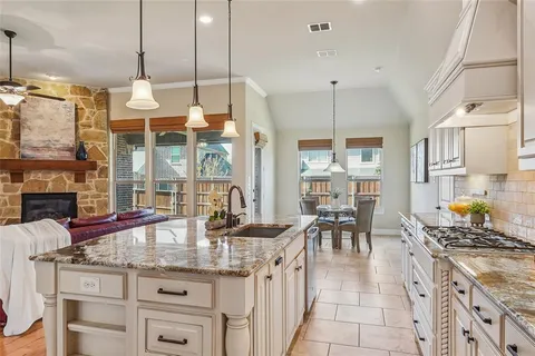 a kitchen with granite countertop a stove a sink a dining table and chairs