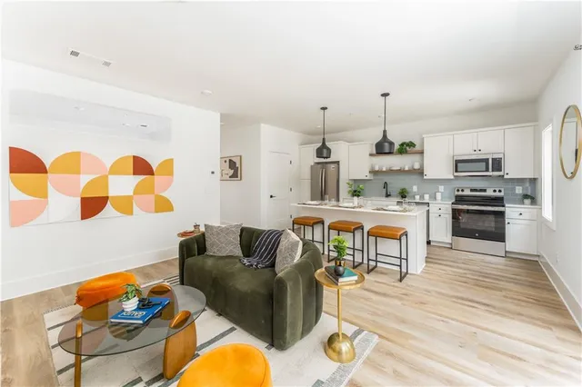 a living room with stainless steel appliances furniture and a kitchen view