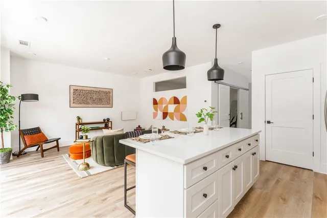 a room with stainless steel appliances kitchen island granite countertop a stove a sink dishwasher and a wooden cabinets with wooden floor