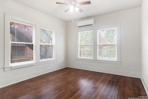an empty room with wooden floor and windows
