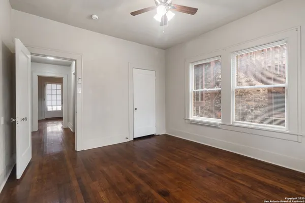 an empty room with wooden floor and windows