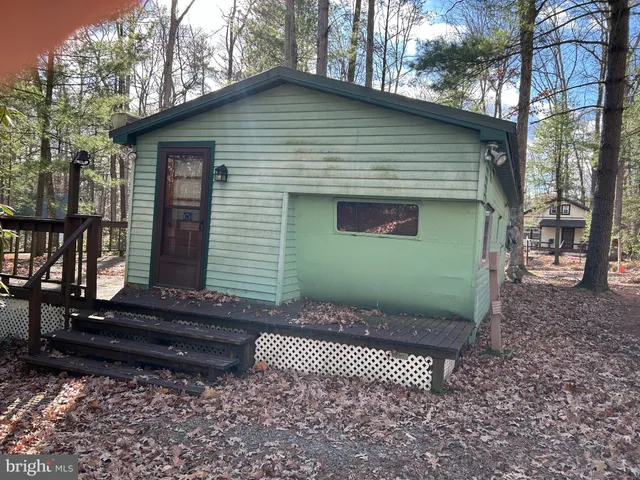 a view of a house with a yard and wooden bench