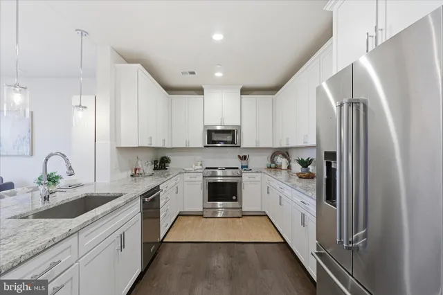 a kitchen with granite countertop stainless steel appliances cabinets a sink and a counter top space