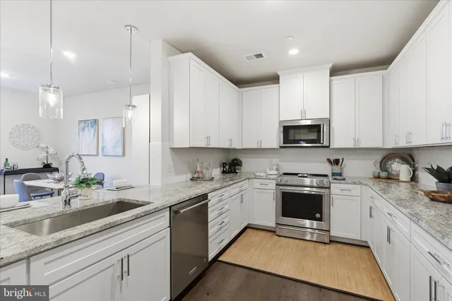 a kitchen with granite countertop white cabinets stainless steel appliances and a sink