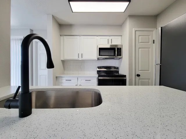 a kitchen with stainless steel appliances kitchen island a stove a sink and a microwave