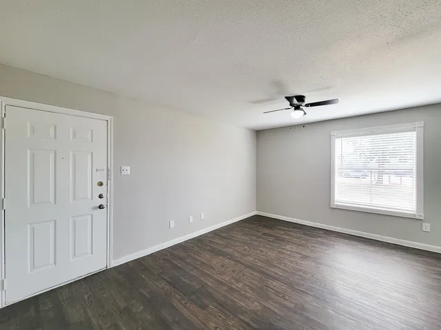 a view of an empty room with a window and wooden floor