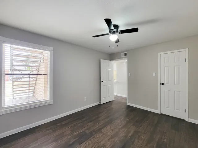 a view of empty room with wooden floor and fan